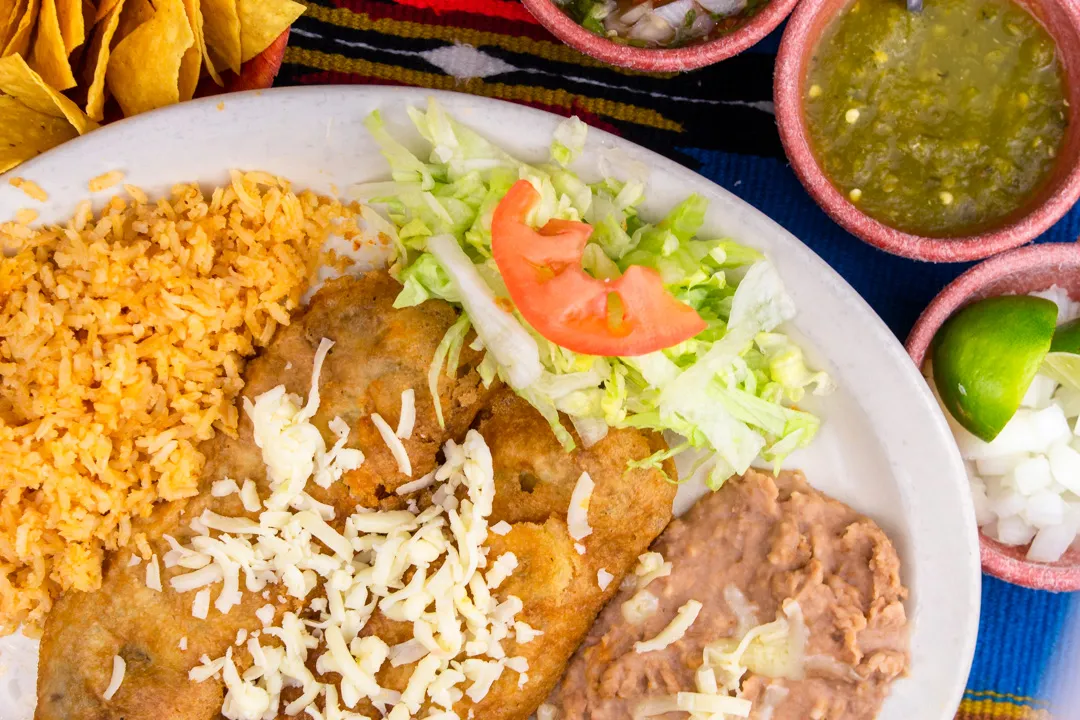 Enchilada plate with rice, refried beans, lettuce and tomato